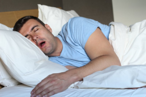 Man asleep in bed with his mouth open