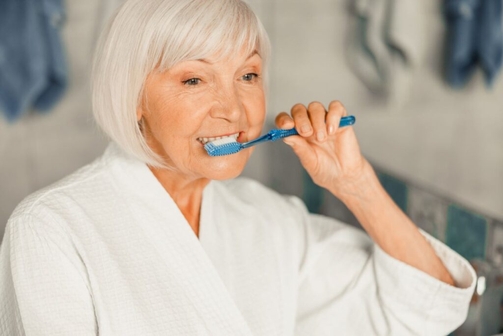 An older woman brushing her teeth.